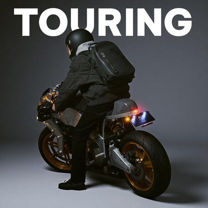 バイクに乗る男性とNONINAの黒い防水バックパック（ツーリング使用シーン）
