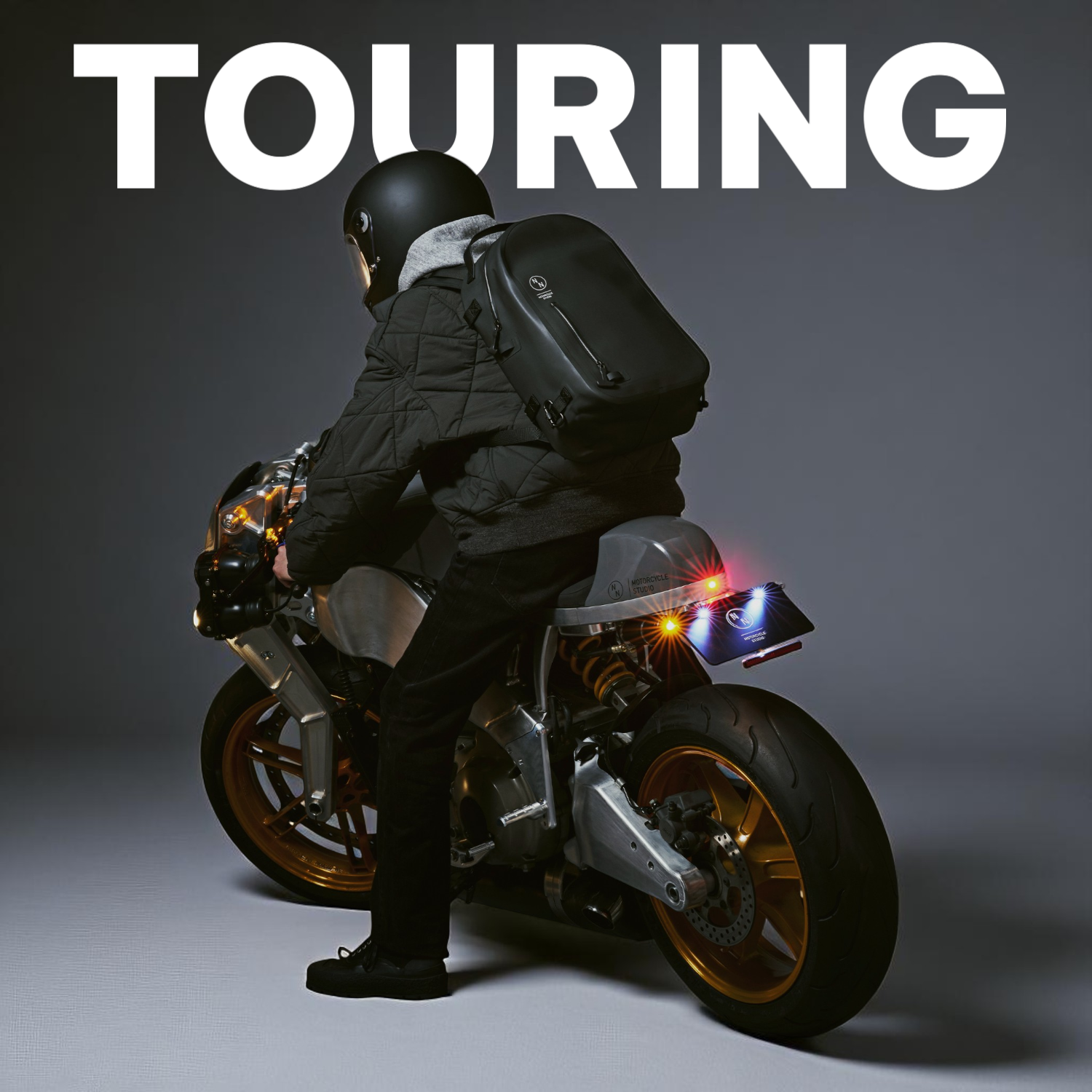 バイクに乗る男性とNONINAの黒い防水バックパック（ツーリング使用シーン）
